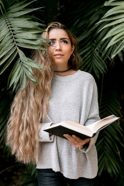 Giovane donna di smiley che tiene un libro all'esterno