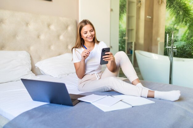 Giovane donna di successo sdraiata su un divano con un computer portatile che paga le bollette online guardando in alto e pensando