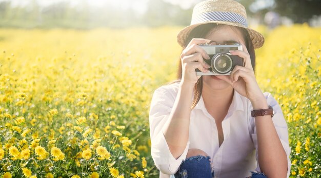 Giovane donna di viaggio in vacanza e utilizzando una fotocamera per scattare foto all&#39;aperto al parco.