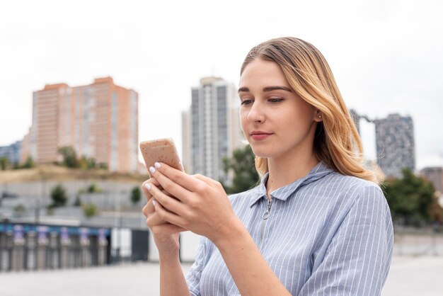 Giovane donna di vista frontale che controlla il suo telefono