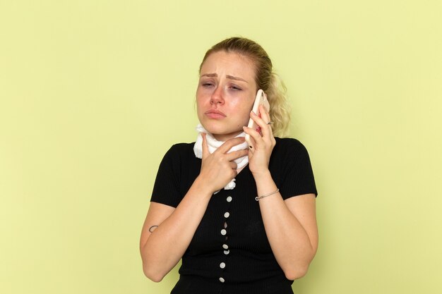 Giovane donna di vista frontale che si sente molto malato e malato parlando al telefono sulla malattia della medicina femminile di malattia della parete verde