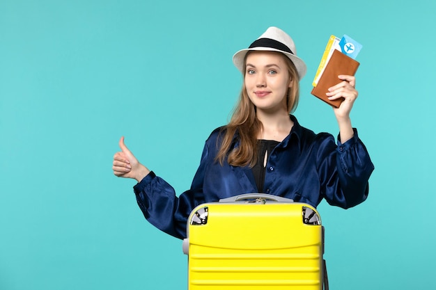 Giovane donna di vista frontale che tiene i biglietti e che prepara per la vacanza che sorride sul viaggio aereo di viaggio di viaggio di mare di viaggio del fondo blu