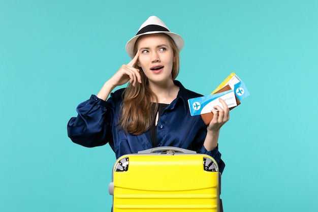 Giovane donna di vista frontale che tiene i biglietti e che si prepara per la vacanza sulla vacanza di aereo di viaggio di viaggio del mare del fondo azzurro