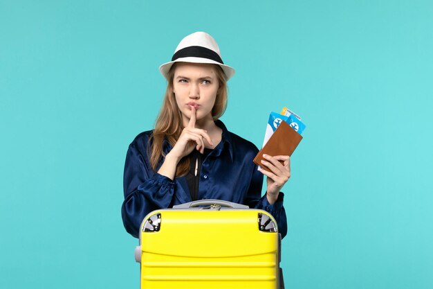 Giovane donna di vista frontale che tiene i suoi biglietti e che si prepara per il viaggio sullo sfondo blu viaggio viaggio aereo mare viaggio vacanza