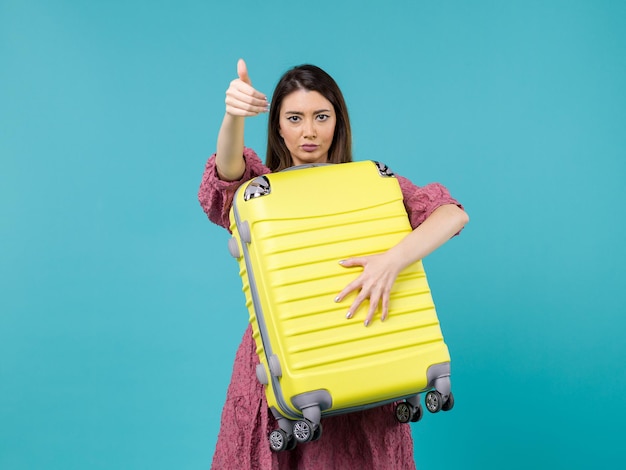 Giovane donna di vista frontale che va in vacanza e che tiene grande borsa sul mare della donna di viaggio di vacanza di viaggio del fondo blu all'estero