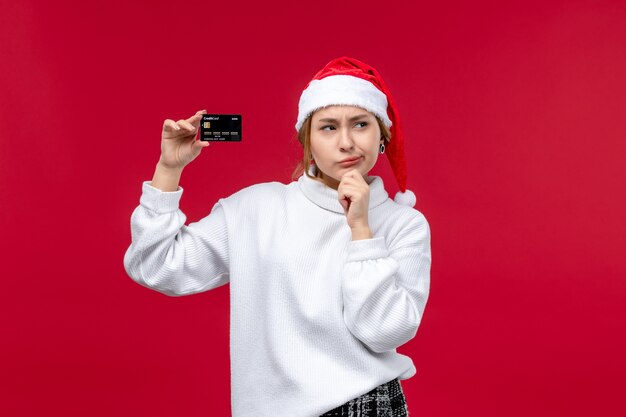 Giovane donna di vista frontale con carta di credito su sfondo rosso