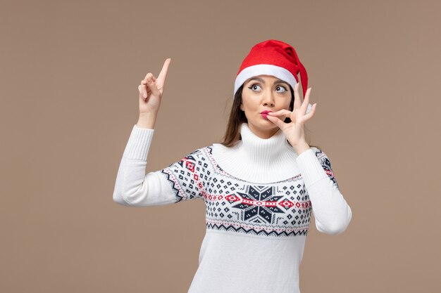 Giovane donna di vista frontale con il cappuccio rosso di natale sul nuovo anno di emozione di natale del fondo marrone scuro