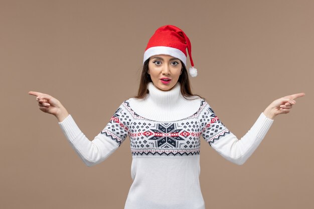 Giovane donna di vista frontale con il cappuccio rosso di natale sull'emozione del nuovo anno di natale del fondo marrone