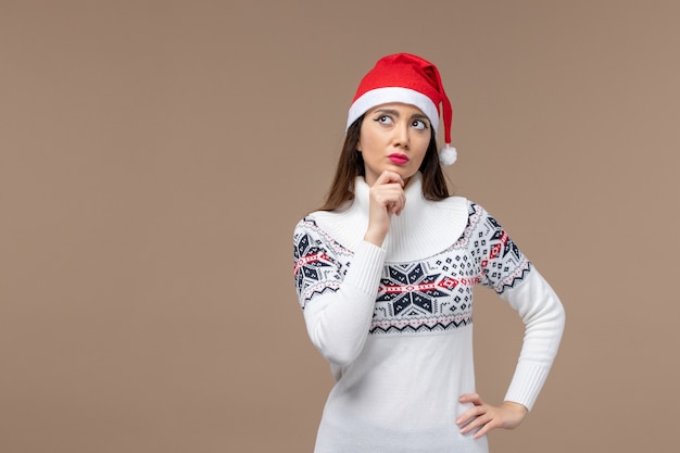 Giovane donna di vista frontale con l'espressione di pensiero sul natale marrone di emozione del nuovo anno del fondo