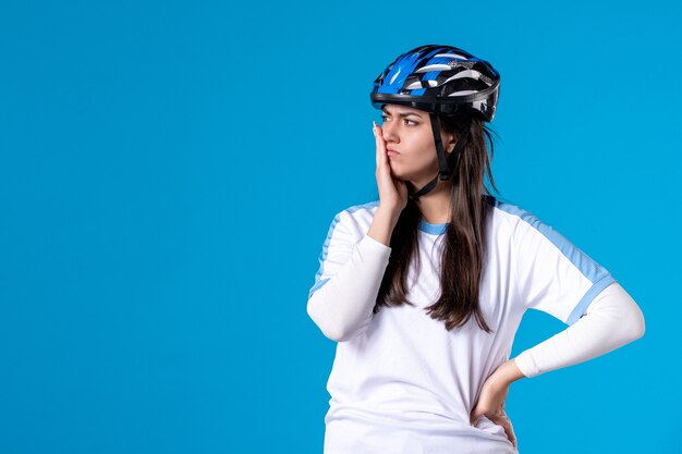 Giovane donna di vista frontale in abbigliamento sportivo con casco sulla parete blu