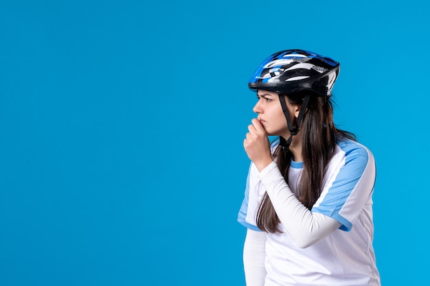 Giovane donna di vista frontale in abbigliamento sportivo con casco sulla parete blu