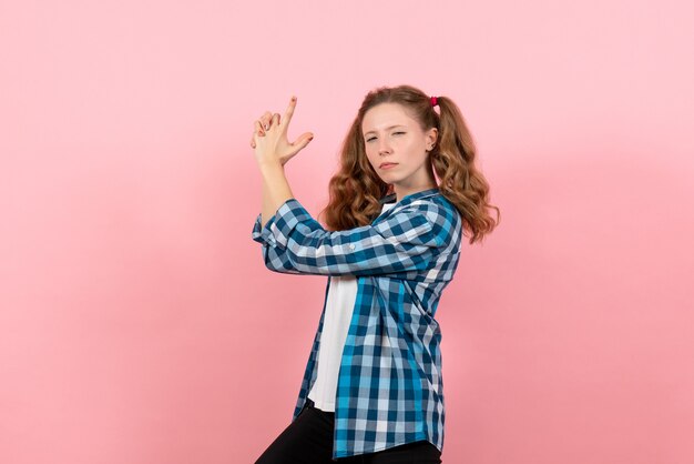 Giovane donna di vista frontale in camicia a scacchi in posa sullo sfondo rosa modello di emozioni di colore della gioventù di donna bambino