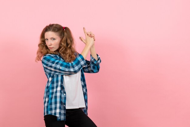 Giovane donna di vista frontale in camicia a scacchi in posa sullo sfondo rosa modello di emozioni di colore della gioventù di donna bambino