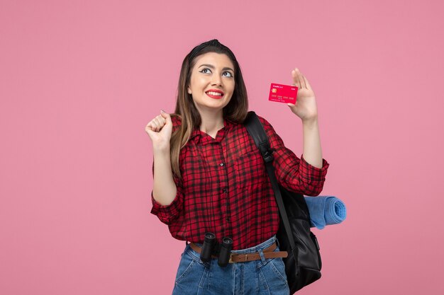 Giovane donna di vista frontale in camicia rossa con carta di credito sulla scrivania rosa donna colore umano