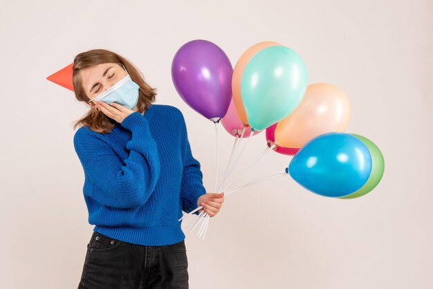 Giovane donna di vista frontale in maschera sterile che tiene palloncini colorati