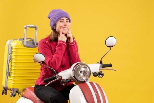 Giovane donna di vista frontale sul ciclomotore che indica il suo sorriso