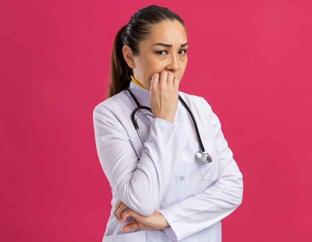 Giovane donna dottore stressata e nervosa che si mangia le unghie