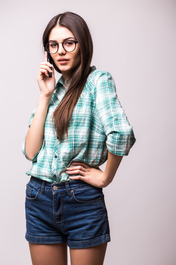 Foto gratuito giovane donna elegante che parla sul telefono cellulare contro il bianco
