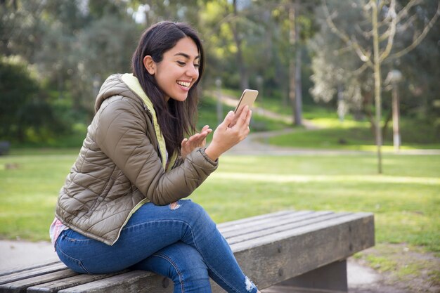 Giovane donna emozionante che chiacchiera online nel parco