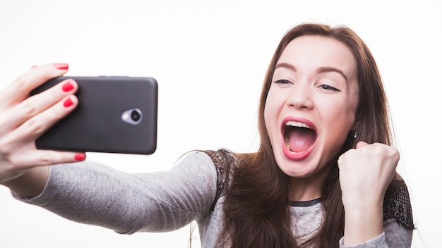 Giovane donna emozionante che fa la foto del selfie tramite il telefono cellulare