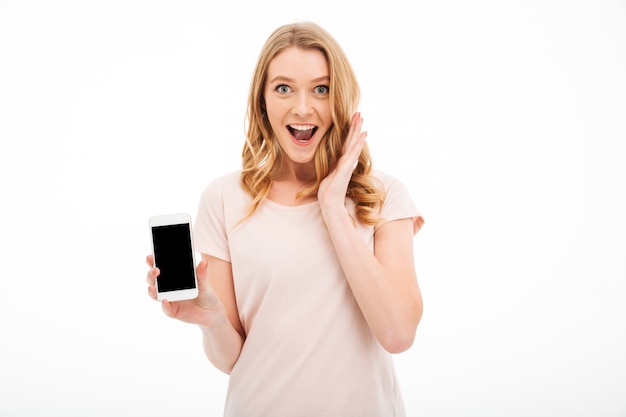 Giovane donna emozionante che mostra esposizione del telefono cellulare.
