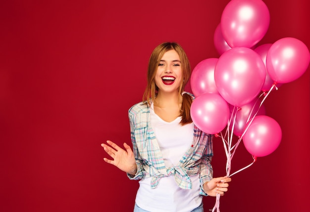 Giovane donna emozionante che posa con gli aerostati rosa