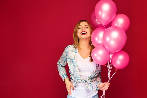 Giovane donna emozionante che posa con gli aerostati rosa