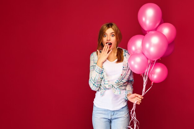 Giovane donna emozionante che posa con gli aerostati rosa