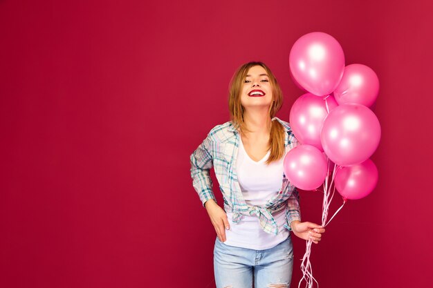 Giovane donna emozionante che posa con gli aerostati rosa