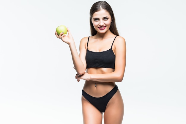 Giovane donna esile che tiene mela rossa. Isolato sul muro bianco. Concetto di cibo sano e controllo del peso in eccesso.