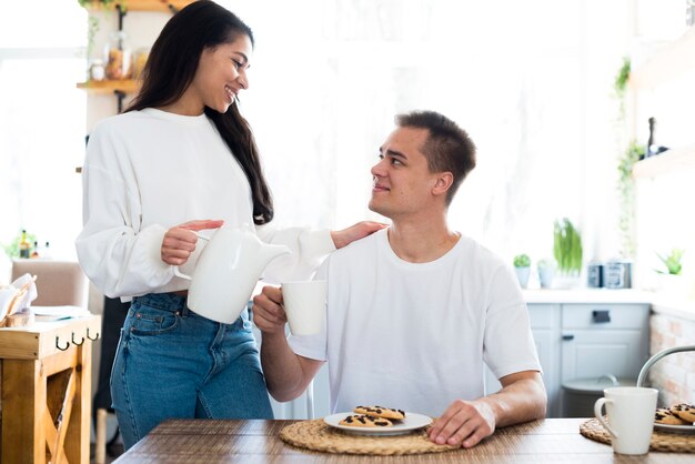 Giovane donna etnica che versa in tazza per il ragazzo