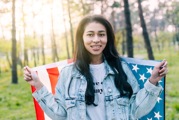 Giovane donna etnica in posa con la bandiera americana