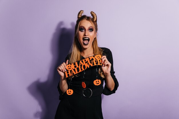 Giovane donna europea con l'acconciatura divertente che propone alla festa. Bella ragazza che celebra Halloween.