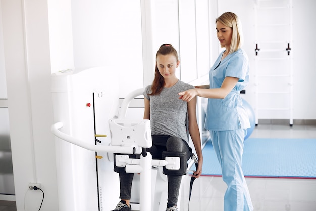 Giovane donna facendo esercizi sul simulatore con terapista in palestra