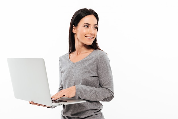 Giovane donna felice che per mezzo del computer portatile.