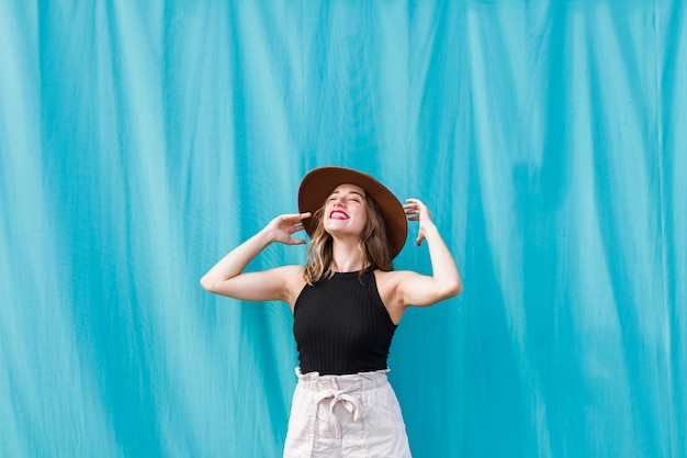 Giovane donna felice che posa con il cappello