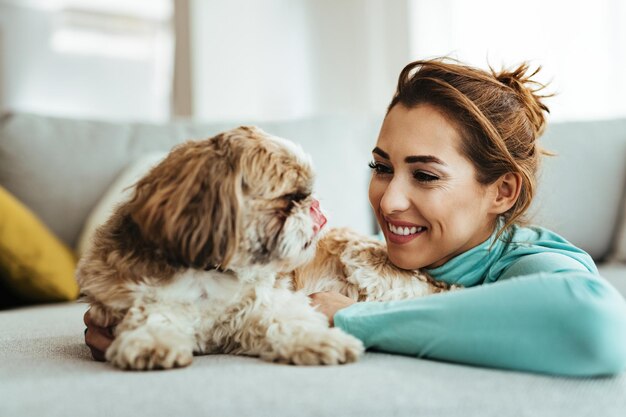 Giovane donna felice che si diverte con il suo cane a casa