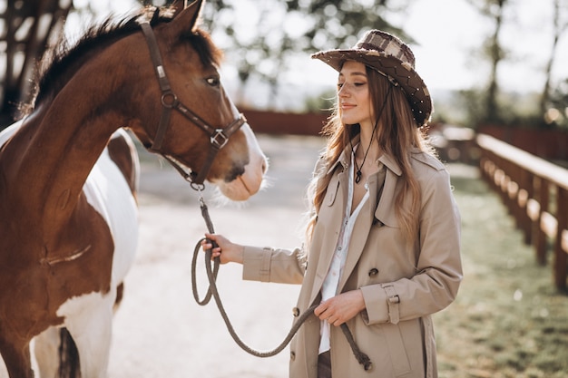 Giovane donna felice con cavallo al ranch