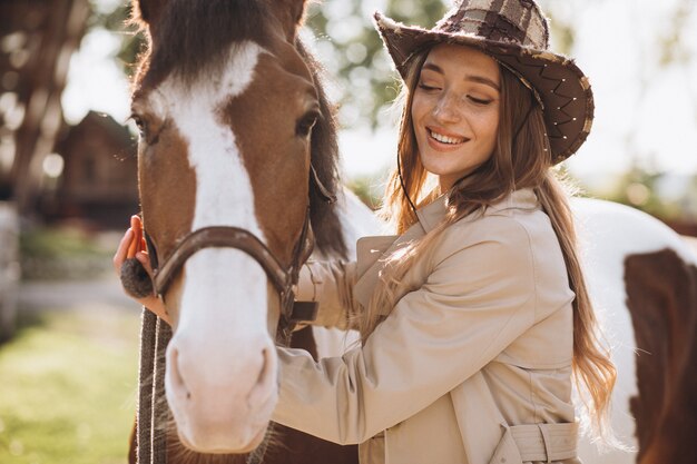 Giovane donna felice con cavallo al ranch