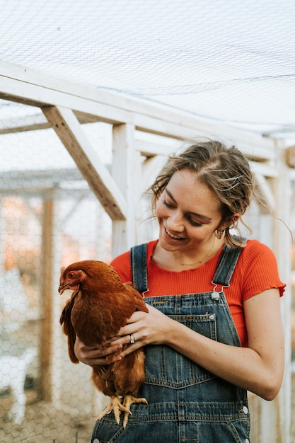 Giovane donna felice con una gallina marrone