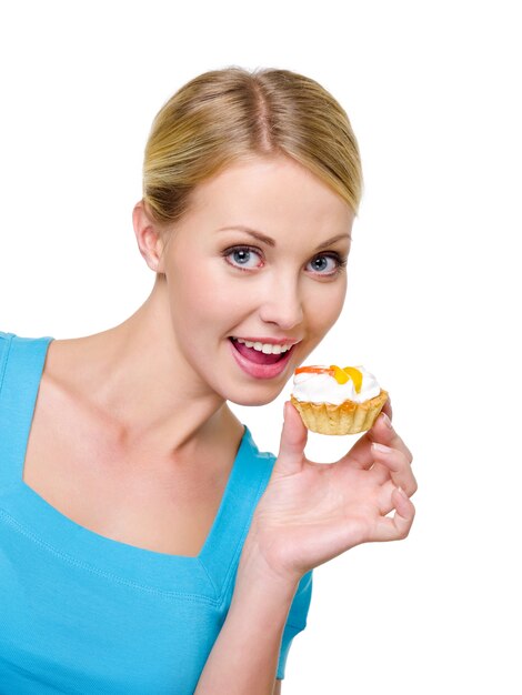 Giovane donna felice di bella gioia che tiene torta dolce vicino al suo fronte