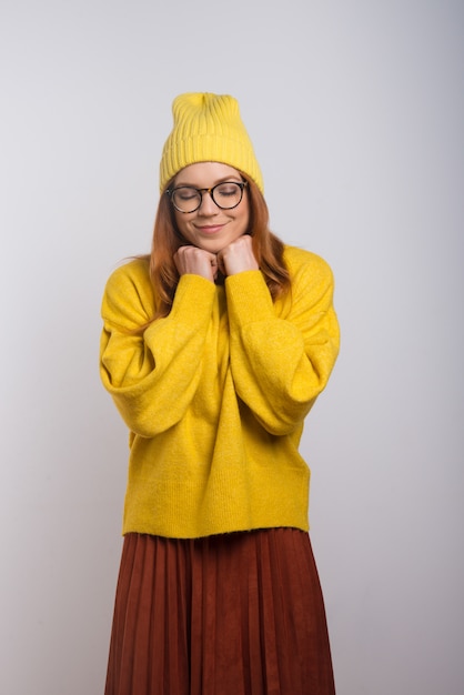 Giovane donna felice in cappello ed occhiali lavorati a maglia