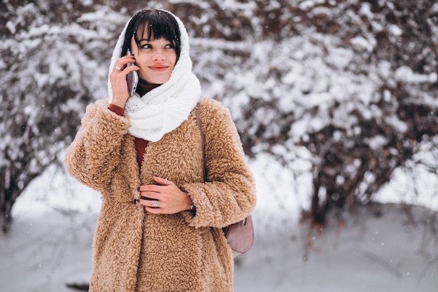 Giovane donna felice in panni caldi in un parco d'inverno