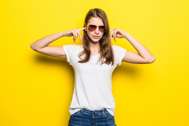 Giovane donna forte in maglietta bianca e blue jeans stare davanti a sfondo giallo studio