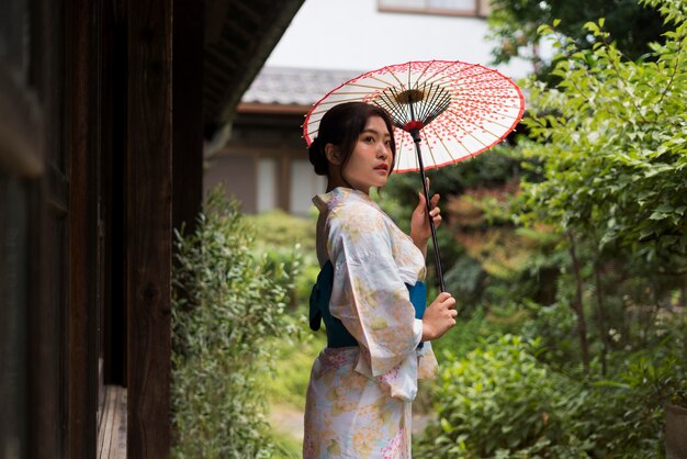 Giovane donna giapponese che indossa un kimono e tiene un ombrello