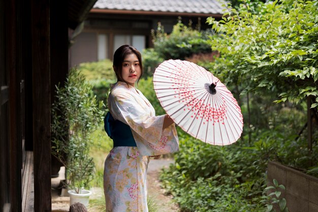 Giovane donna giapponese che indossa un kimono e tiene un ombrello