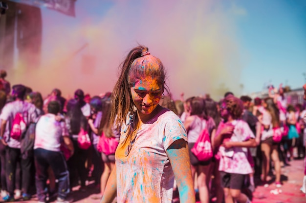 Giovane donna godendo con colori holi nella folla