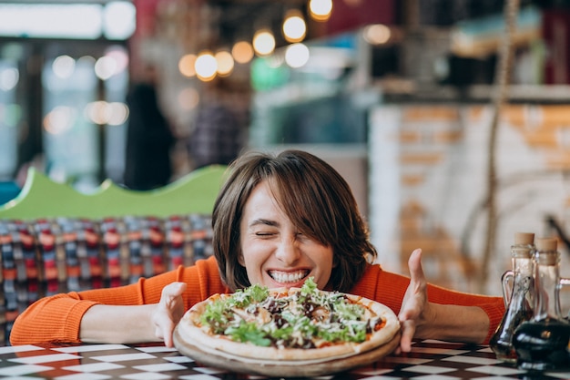 Giovane donna graziosa che mangia pizza al bar della pizza