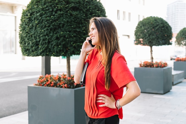 Giovane donna graziosa che parla sul telefono cellulare in città