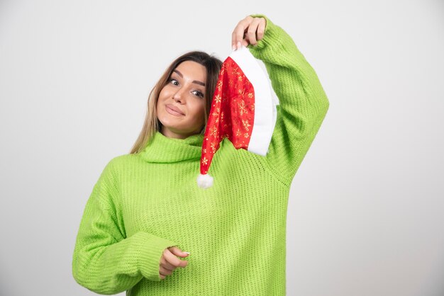 Giovane donna graziosa che posa in cappello rosso di Babbo Natale.